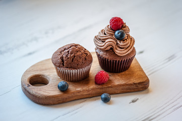 Tasty cupcakes decorated with chocolate cream on a white wooden table. Process of cupcakes preparation. Homemade cupcake. Copy space. Soft focus.