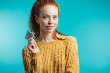 Attractive ginger adult woman holding condom calling to prevent sexually transmitted diseases or...