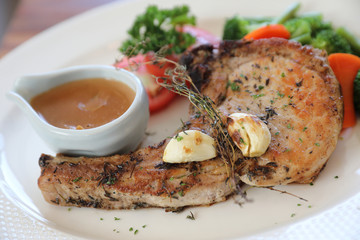 grilled pork chop with vegetable on dish with wood table background