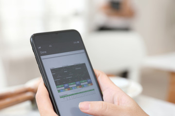 Female hand with smartphone trading stock online in coffee shop , Business concept