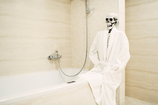 Human skeleton sitting on the edge of the bath