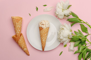 Delicate cream ice cream on a white plate. Flatlay on a pink background with white peonies. Top view. Copy space