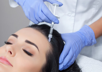 Fototapeta premium Procedure of mesotherapy. The doctor cosmetologist makes the procedure of mesotherapy in woman's head. Strengthen hair and their growth.