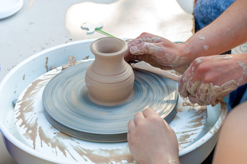 Making it together. A side view of a mountain that teaches a child to make a ceramic pot on a wheel of pottery
