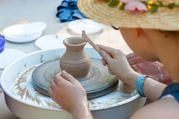 Making it together. A side view of a mountain that teaches a child to make a ceramic pot on a wheel of pottery