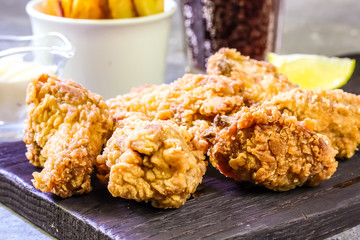 Fried chicken wings on concrete table. Breaded Crispy fried chicken wings with French fries with cheese sauce and soda