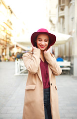 Cute smiling woman in coat and on street tourist town