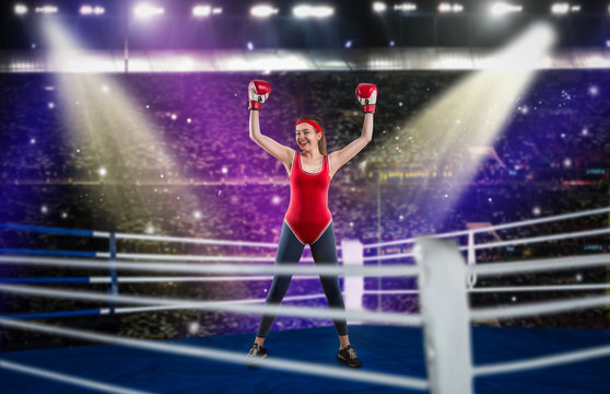 Female boxer in red sportswear hands up on ring