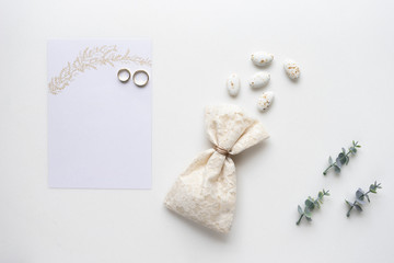 Wedding invitation card, candy, rings and oregano branches. Top view.