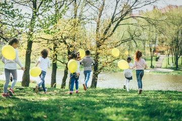 Children with yellow balloons running in the park