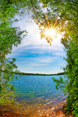 Panele Szklane  Jezioro z drzewami i jasnym słońcem w upalny letni dzień