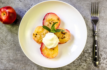 Baked peaches with ice cream on a plate on a gray metal background