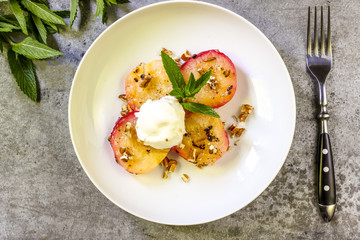 Baked peaches with ice cream on a plate on a gray metal background
