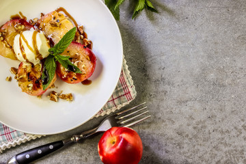 Baked peaches with ice cream on a plate on a gray metal background