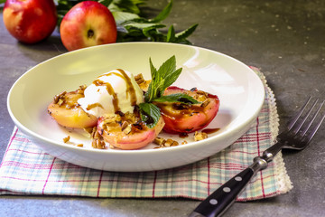Baked peaches with ice cream on a plate on a gray metal background