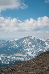 A beautiful view of the snow-capped mountains of the Carpathians from the top of Goverly in spring in a beautiful sunny day with light clouds. Carpathians, Goverla, Ukraine.