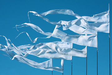A waving white long triungular flags on a background bright blu sky