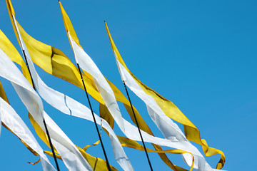 A waving yellow-white long triungular flags closeup on a background bright blu sky