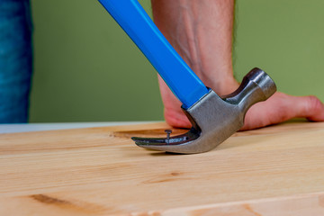 Pulling the nail out of the board. Concept of renovation, housework. The man is holding a nail in the hand. Handyman, DIY.