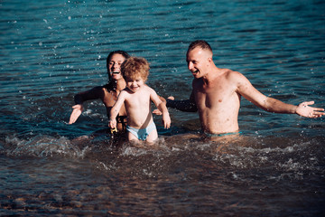 Happy Young Family with Little Kid Having Fun at the Beach. Joyful Family. Travel and Vacation. Summer Vacations.