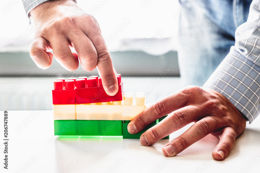 Poster the businessman arranges blocks of different colors. the man arranges the blocks to form stairs. gro
