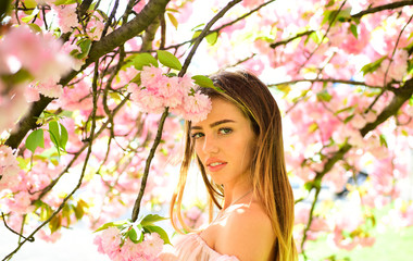 Obraz na płótnie Canvas Woman posing under Japanese cherry, beauty and harmony concept. Sexy girl enjoying fragrance of flowery tree. Portrait of lovely blond female with full lips on natural background