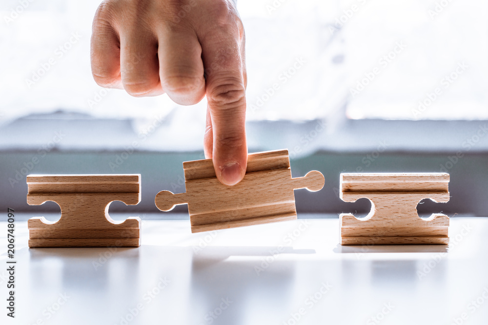 Poster hand holding a wooden jigsaw puzzle with blank space. there is a matching puzzle next to it. the con