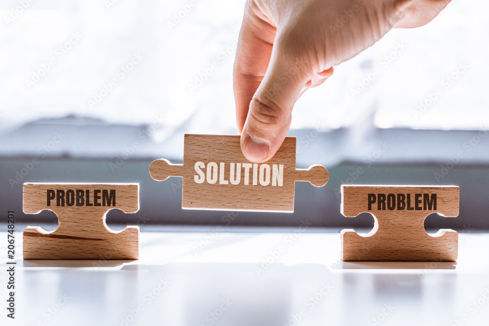 Poster hand holding a wooden puzzle with the word solution. there is a matching puzzle next to it with the 