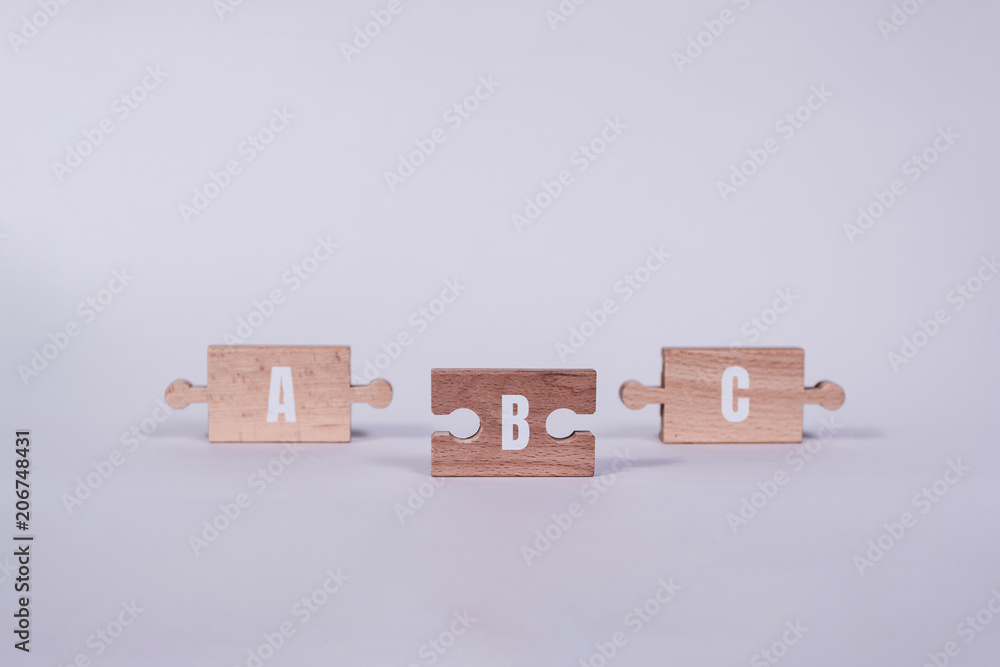Poster wooden jigsaw puzzle with a, b, c words. there is a matching puzzle next to it. the concept of solvi