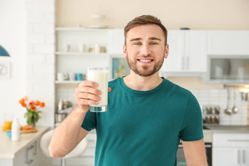 Young man with glass of tasty milk at home