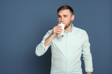 Young man drinking tasty milk on color background