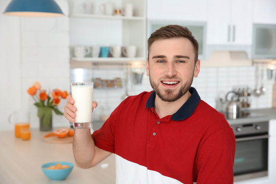 Young man with glass of tasty milk at home