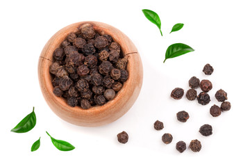 Black peppercorn in a wooden bowl decorated with green leaves isolated on white background. Top view