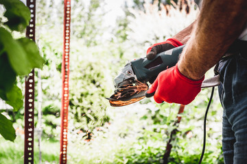 The man is sharp with the mower's knife with a grinder, sparks fly from work. Using an angle...