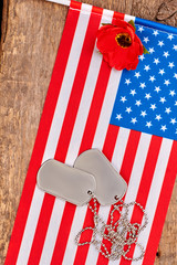 Dog tags, red poppy and american usa flag. Wooden desk bakground.