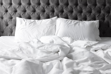Comfortable bed with white linen and pillows at home