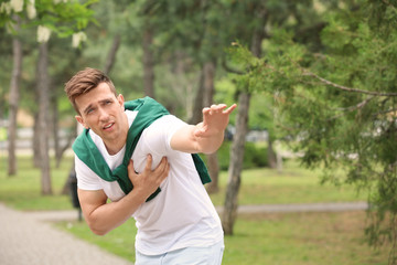 Young man asking for help while having heart attack outdoors