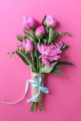 Bouquet of beautiful peony flowers on color background, top view