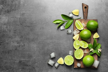 Composition with fresh ripe limes and ice cubes on gray background, top view