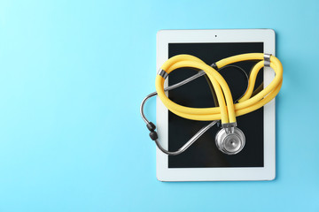 Fototapeta na wymiar Stethoscope and tablet on color background, top view. Medical equipment