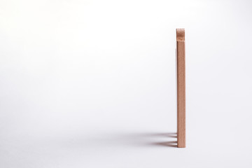 Wooden block isolated on a white background. The wooden block casts shadows, and other blocks are stacked behind it.
