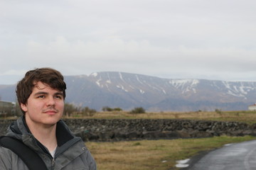 Tourist aged 20 to 25 poses in front of a mountainous region in Reykjavik Iceland