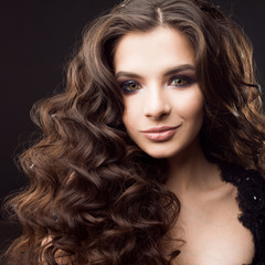 Fototapeta premium Portrait of a young attractive woman with gorgeous curly hair. Attractive brunette