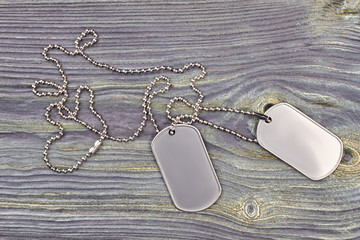 Military Dog Tag close up. Dog tag with a chain on grey wood background, top view.