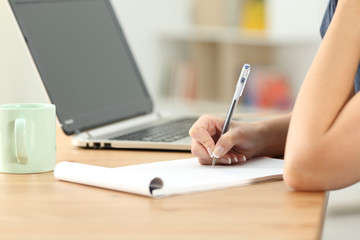 Female hand writing notes in a notebook on a desk