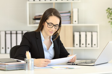 Office worker wearing eyeglasses reading a report