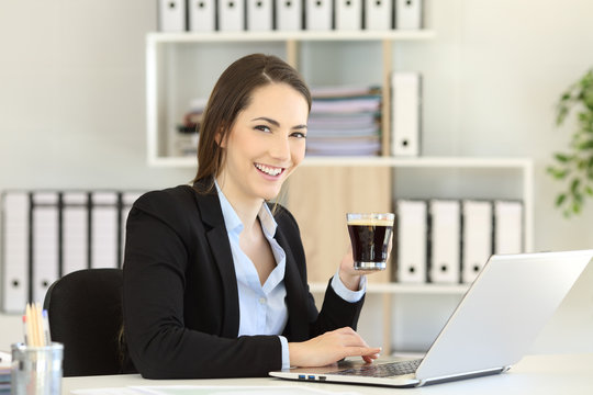 Office worker holding a coffee cup looking at camera
