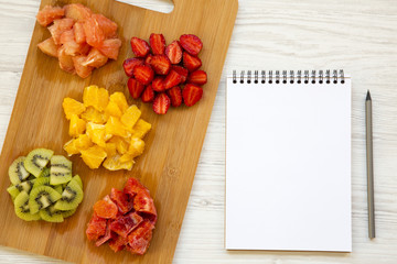 Various chopped fruits with notebook, top view. Flat lay. From above.