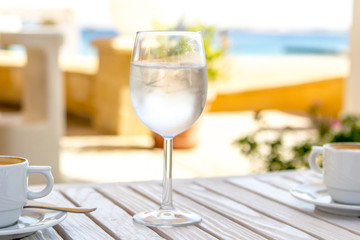 glass with water and ice on a white wooden table on a sunny summer day