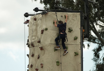 Young Boy Climbing an Outdoor Rock Wall During the Day